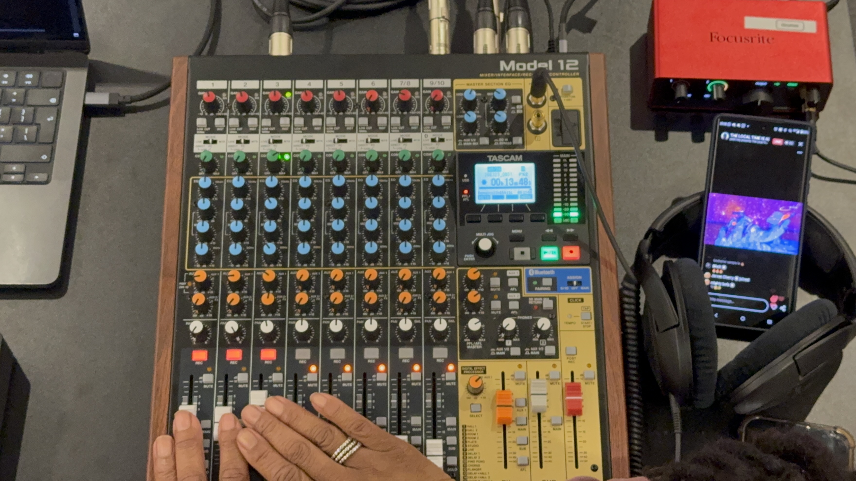 Audio mixer beside a phone showing the livestream visual feed