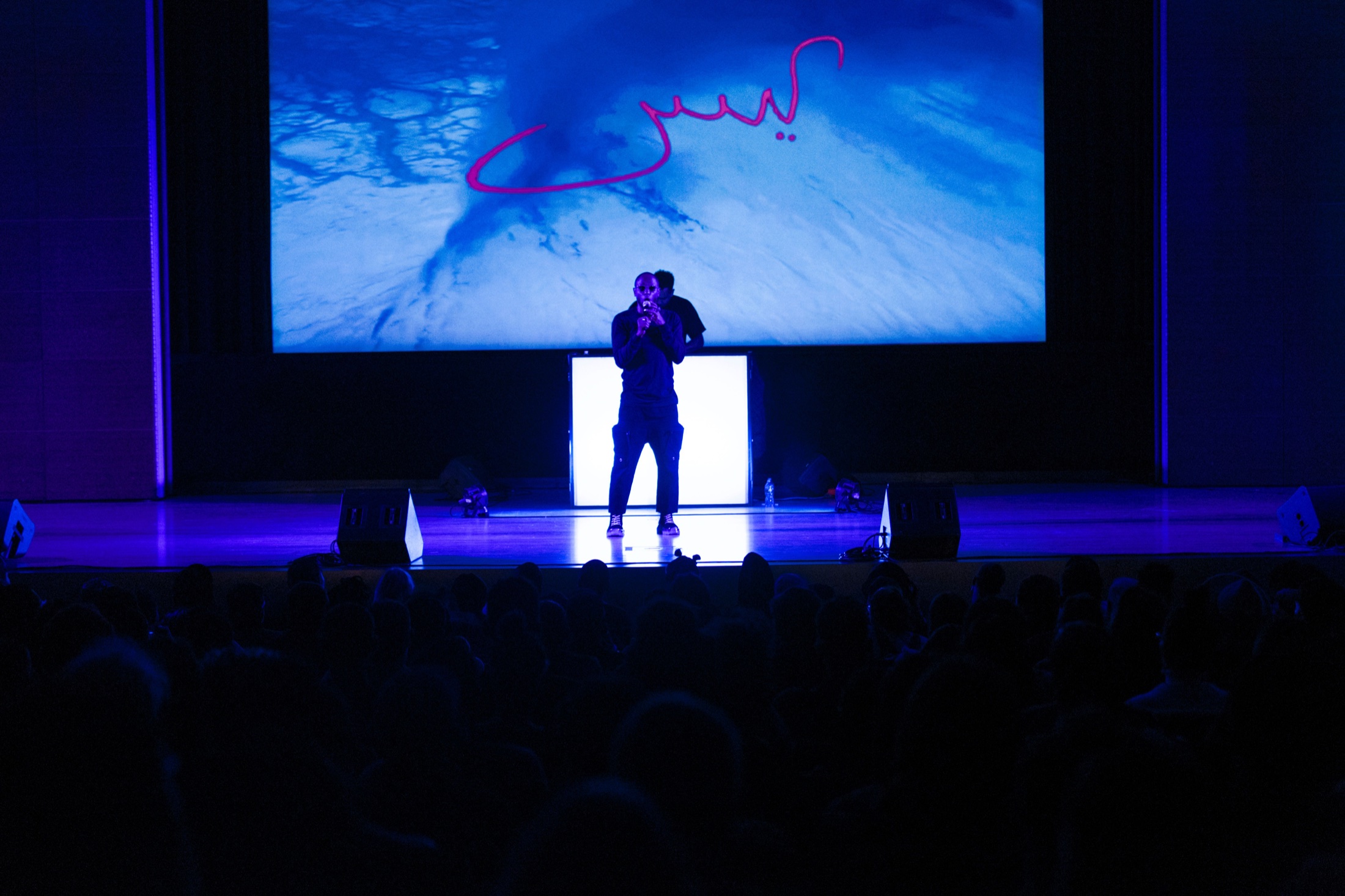 Yasiin Bey centered under the Negus projection during the Brooklyn Museum performance