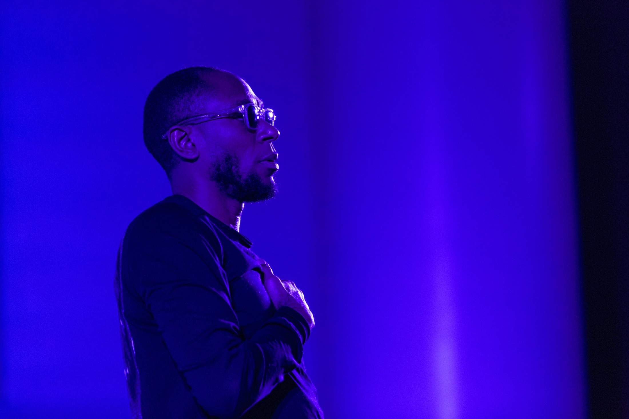 Portrait profile of Yasiin Bey in purple stage light