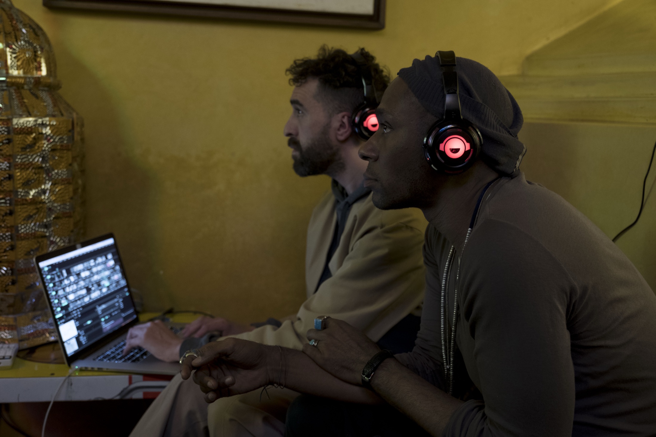 Yasiin Bey and a collaborator listening beside a laptop during the Marrakech installation